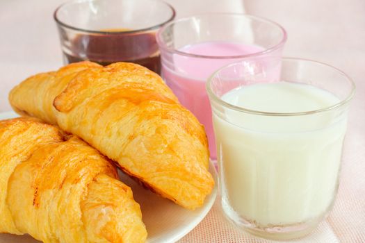 croissants served with glass of Fresh milk, coffee on pink background. Breakfast concept.