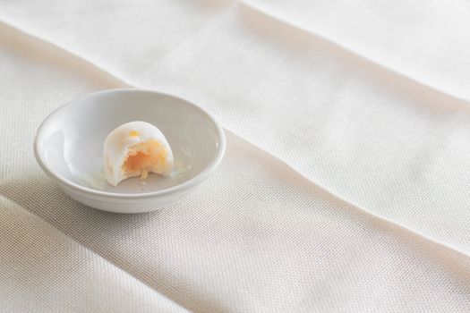 Puff moon cake with sweet mung bean and salt egg yolk in white bowl on table with copy space for your text.