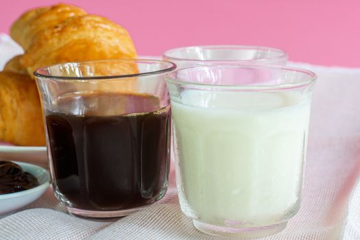 croissants served with glass of Fresh milk, coffee on pink background. Breakfast concept.