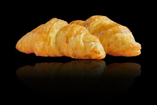 Two croissants with reflection on black background.
Homemade bakery for breakfast.
