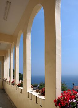 A view of the blue sea through the arches of a colonnade terrace
