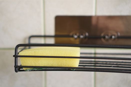 Sponge for washing dishes on metal shelf in kitchen. Concept of cleaning. Close-up interior. No people.