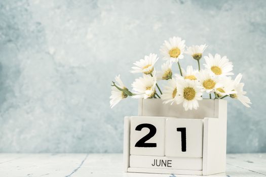 White cube calendar for june decorated with daisy flowers over blue background with copy space