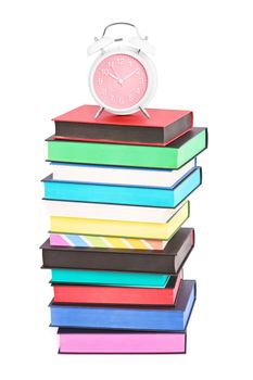 An alarm clock on top of stack of colorful books with different sprayed edges, isolated on white background. Education and time concept.


