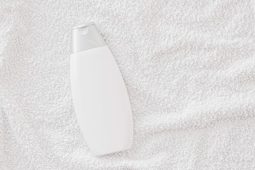 Blank label cosmetic container bottle as product mockup on white towel background, hygiene and healthcare