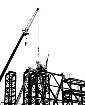 Steel construction with crane and workers in silhouette
