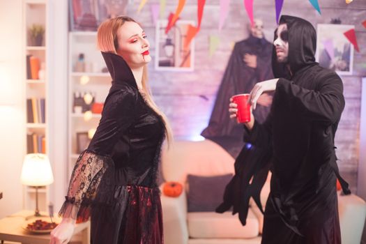 Man dressed up like a grim reaper dancing with beautiful vampire woman at halloween celebration.