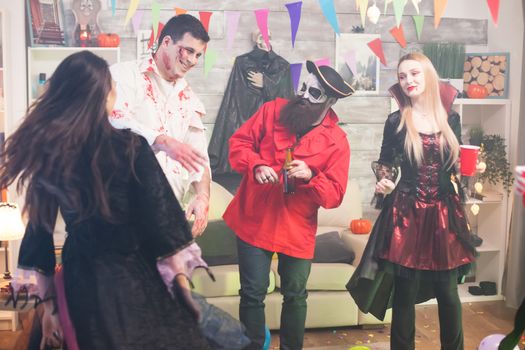 Man dressed up like scary zombie with blood on his face at halloween celebration with his friends.