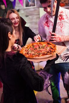 Excited group of friends about pizza at halloween party.