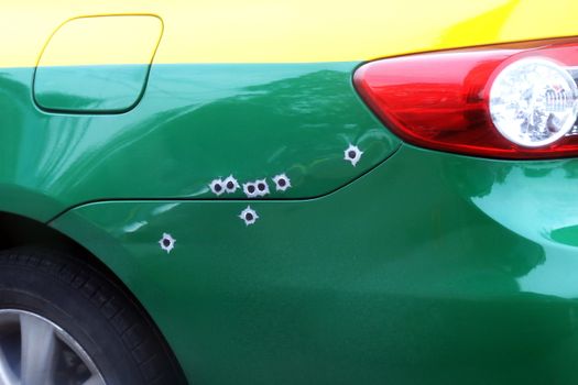 the marks bullets hole on the car bonnet, shrapnel bullet shot cracked hole on car surface,  shoot the car
