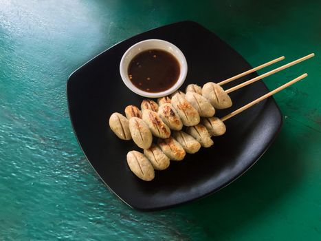Meat balls grill and sauce in the black plate isolated green wood table top view
