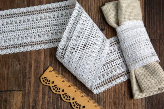 knitted white openwork linen ribbon tapes in rural style of rustics cotton eco natural on wood ground