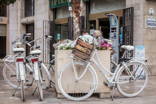 Valencia, Spain - June 16, 2017: Verrassend Valencia rental bicycle parked on a small tourist square in the historic city center on a summer day