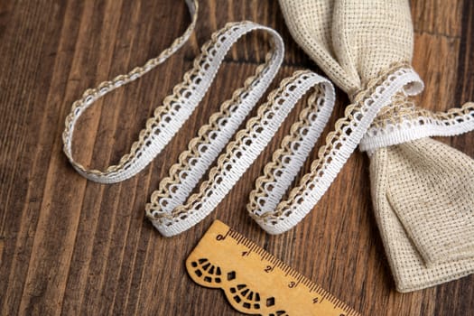 knitted white openwork linen ribbon tapes in rural style of rustics cotton eco natural on wood ground