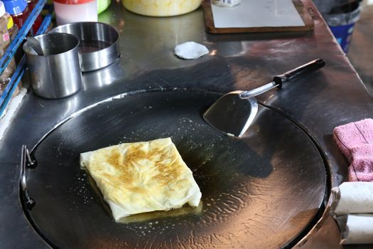 Roti eggs fried (thai word) in a night market street, Indian food, Chapati flatbread, roti canai, dal, curry, teh tarik or pulled tea, acar. Famous indian cuisine