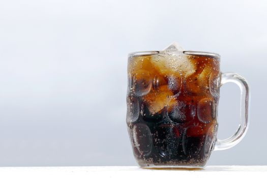 black cola soda in glass with ice cubes for refreshments feel, beverage cola and cubes ice refreshing cool in glass on grey background
