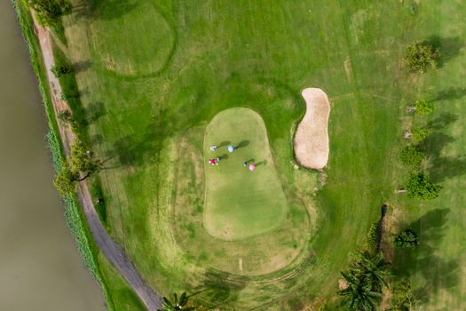 Aerial top view photo from flying drone of Golf Course, Lush green grass on golf course with path for golf cart, Group playing golf and flag 