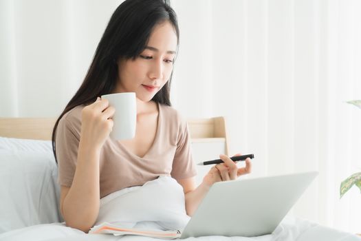 Beautiful woman Asian people are happily using their laptops at home. Working from home is a new normal in the situation where the coronavirus is spreading.