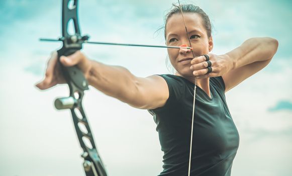 attractive woman on archery, focuses eye target for arrow from bow.