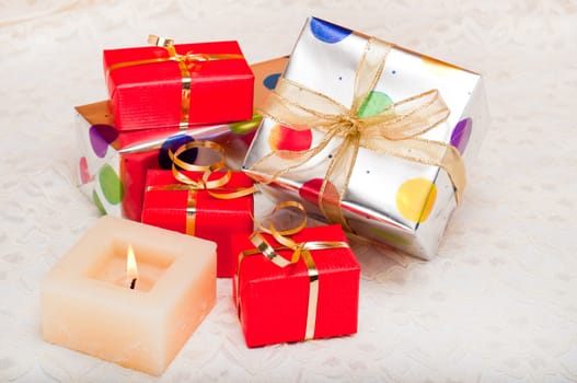 Beautiful colorful gift boxes and candle on a backround of off-white lace