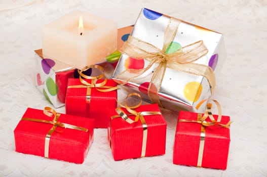 Beautiful colorful gift boxes and candle on a background of off-white lace