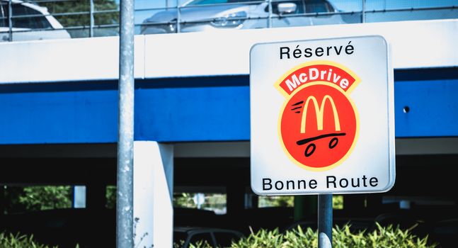 Libourne, France - May 26, 2017: Road sign indicating a place reserved for McDrive customers in the parking lot of a McDonald s restaurant on a spring day