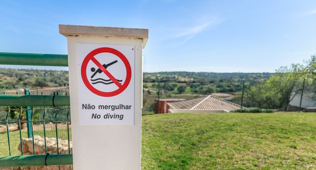 No Diving sign in English and Portuguese next to a swimming pool