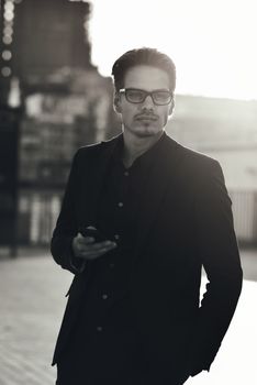 Serious Caucasian businessman dressed at classic wear standing at the street.