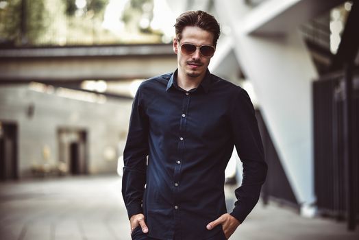 Young stylish and confident happy handsome businessman model in shirt lifestyle in the street in sunglasses