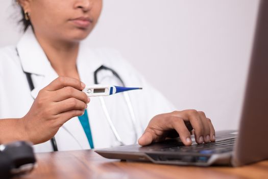 Doctor explaining how to use fever thermometer to patient through online on laptop - Concept of telehealth, or telemedicine with patient during coronavirus or covid-19 pandemic