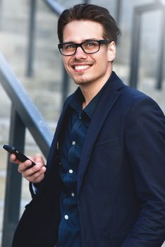 Happy caucasian businessman in glasses dressed at classic wear standing at the street.