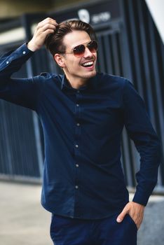 Young stylish and confident happy handsome businessman model in shirt lifestyle in the street in sunglasses