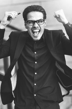 Happy caucasian businessman in glasses dressed at classic wear standing at the street.