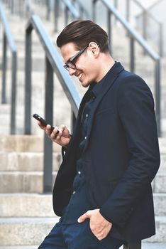 Happy caucasian businessman in glasses dressed at classic wear standing at the street.