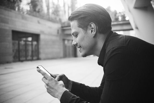 Smiling businessman use a smartphone at street.