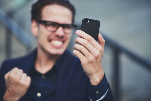 Happy caucasian businessman in glasses dressed at classic wear standing at the street.