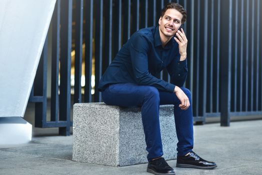 Successful caucasian businessman with smartphone at street in the city.