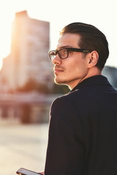 Serious Caucasian businessman dressed at classic wear standing at the street