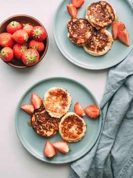 Sweet cheese pancakes on plate served strawberries. Cottage cheese pancakes, syrniki, ricotta fritters, curd fritters. Top view or flat lay. Vertical.