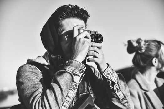 Stylish man photographing on retro camera. Tourist stay on the bridge and make a photo.