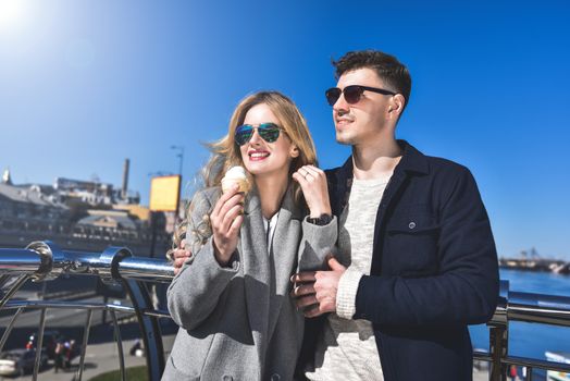 Beautiful couple stay at city embankment and eating the ice cream