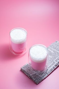 Summer drink concept. Strawberry pink milk with froth milk in clear glass on pink background. 