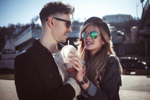 Cute couple having fun walking at the street and drink cocktails , good day