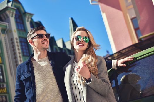 Couple in sunglasses standing near the car and looking for new apartment