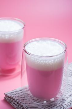 Summer drink concept. Strawberry pink milk with froth milk in clear glass on pink background. 