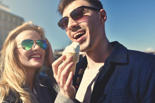 Happy romantic caucasian couple in sunglasses. Funny girl eat the ice cream