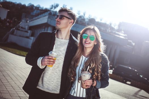 Cute couple having fun walking at the street and drink cocktails , good day