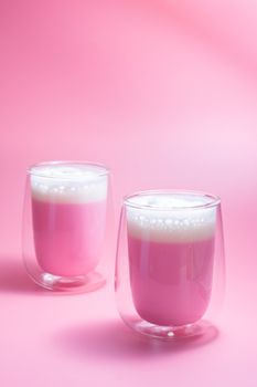 Summer drink concept. Strawberry pink milk with froth milk in clear glass on pink background. 