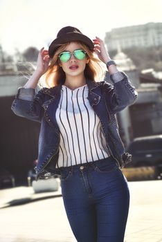 Beautiful girl with juice in sunglass walking at the street on urban style