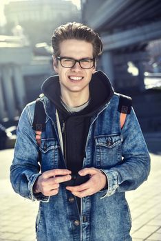 Smiling man with glasses stay at city with a backpack